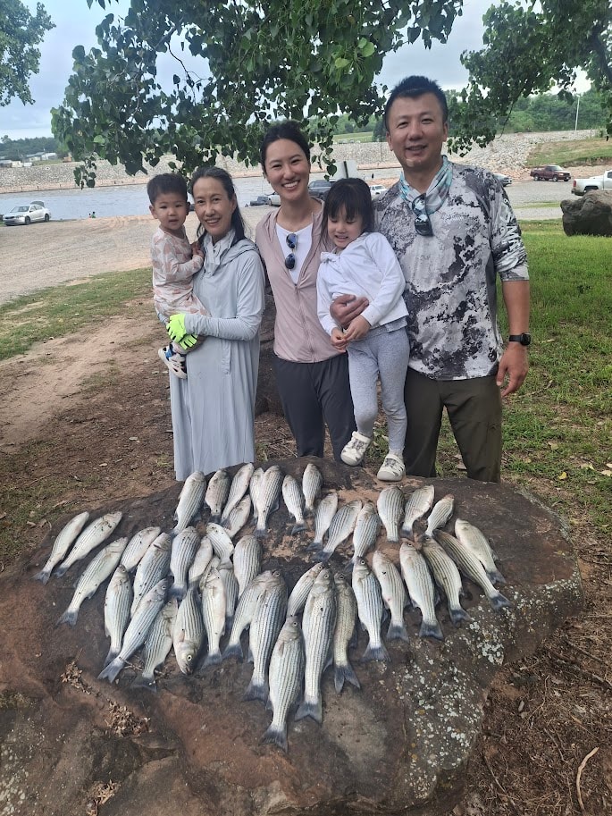 Family with two young kids and a big striper catch on the rocks