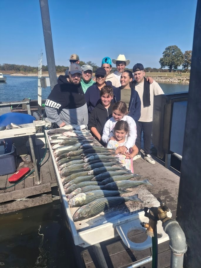 Large group with kids posing behind a full cleaning table of stripers