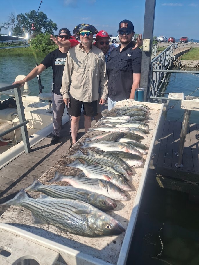 Four guys with a great striper catch at the dock