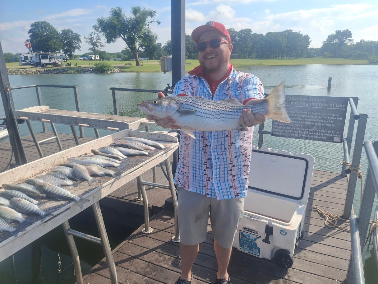 Happy angler holding a big striper at the cleaning dock